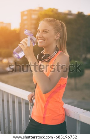 Beautiful sporty woman drinking water while resting from exercise.Refreshment after practicing
Image is intentionally toned.