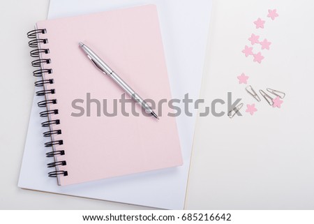 top view of pen on pink notebook and office supplies at workplace