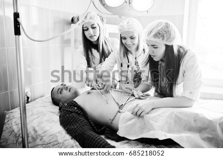 Young talented surgeons performing operation on their patient. Black and white photo.