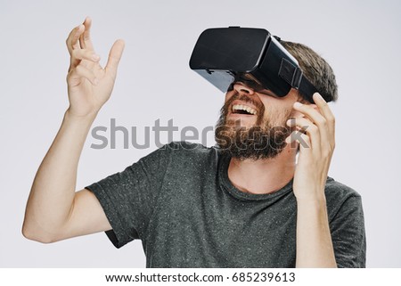 A man with a beard playing 3d games in glasses virtuality on a light background                               