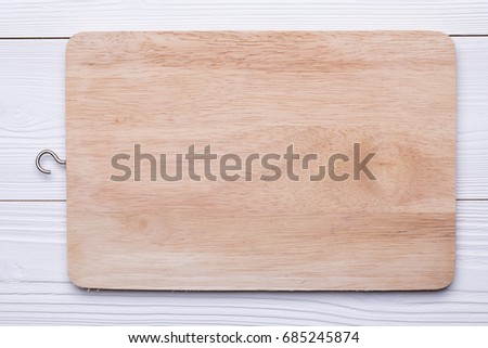 Wooden cutting board on textured white wood table, top view