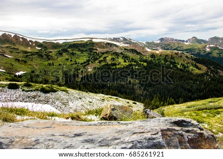 rocky mountains with snow, grass, and trees