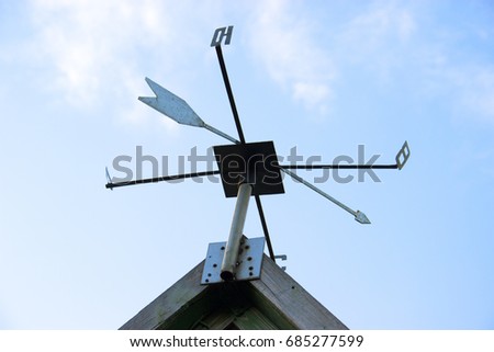 Weathervane Against a Radiant Blue Sky. The sides of the world are marked with Cyrillic letters. Weather vane of Russia and CIS countries,