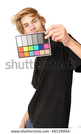 A man holds up an 18 % gray white balance card with test colors on it to calibrate the colors perfectly in post production.