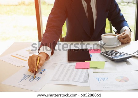 Business man working with new startup project hand pointing graph discussion and analysis data charts and graphs and using a calculator to calculate  numbers.Business finances and accounting concept
