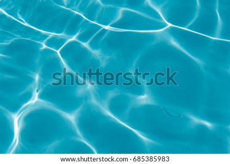 Rippled water in swimming pool with sun reflection