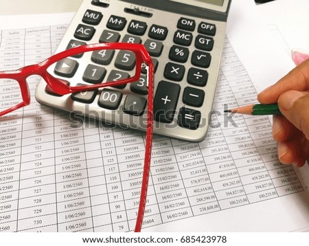Holding pencil in hand with have paper , red eyeglasses  and calculator