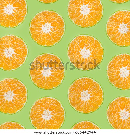 Sliced orange fruit on soft pastel green background
