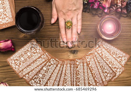 Fortune teller female hands and tarot cards on wooden table. Divination concept.  Royalty-Free Stock Photo #685469296