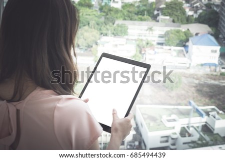 A business girl is playing a smartphone in high building with city view is working on tablet in a high building