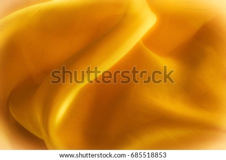 The photo is blurred. Texture, background, pattern. Yellow silk fabric. Abstract background of luxury Yellow fabric or liquid wave or wavy grunge texture. The whole background.