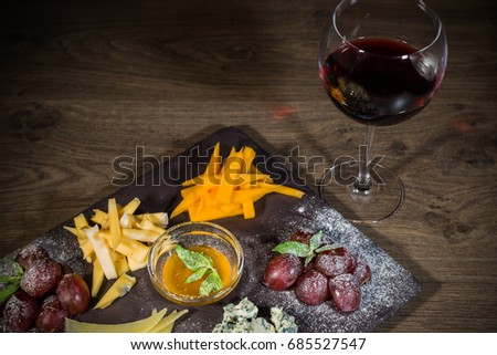 Cheese mix with honey and grapes on a stone background.