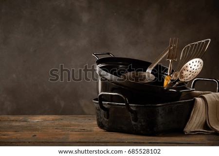 Set of kitchen pots and utensils standing on wooden countertop