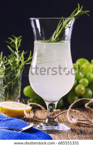 Gin tonic coctail with rosemary and lemon on wooden kitchen table