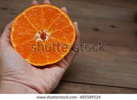 Close up, Half an orange at hand,On a dark wood floor,copy space.