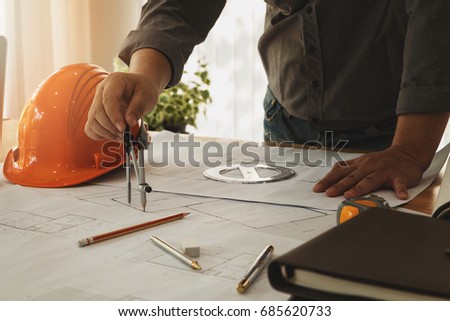 An architect or engineer working on blueprint, An architect or engineer uses a divider gauge on the blueprint., architectural concept