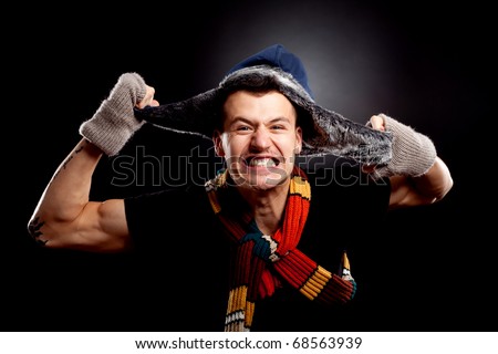 picture of a young man in winter clother pulling his furry hat