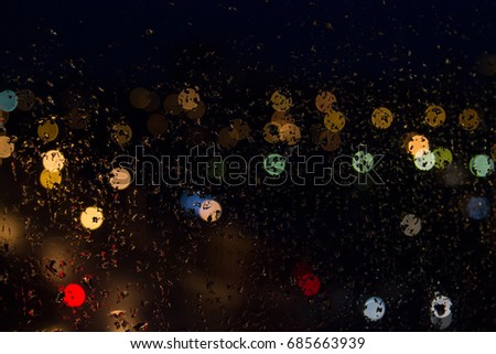 Rain drops on the glass colored lights at night.