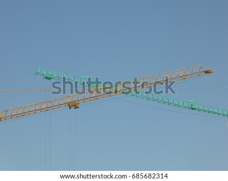 Two cranes green and blue with sky background