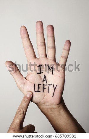 the text I am a lefty written in the palm of a left-handed man, against a beige background Royalty-Free Stock Photo #685709581