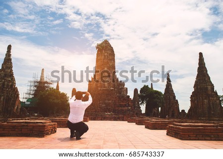 Businessman take a photo of ancient Buddha with smartphone .