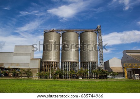 View of meadow silos tank against blue sky