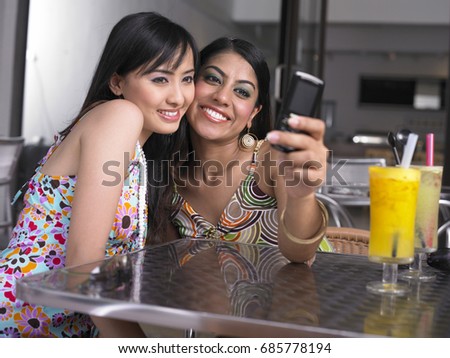 Two women at outdoor garden cafe, taking pictures