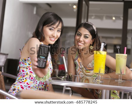 Two women at outdoor cafe, taking pictures