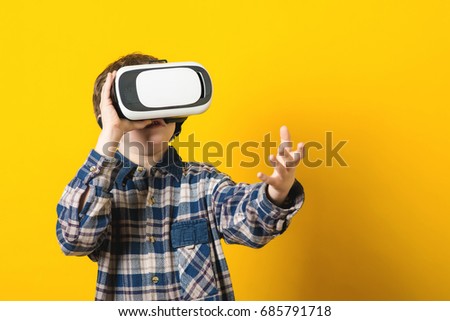 The boy wearing virtual reality goggles over the yellow background.
