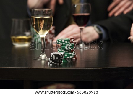 Poker chips on black table and red and white wine background Royalty-Free Stock Photo #685828918