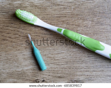 Toothbrush and interdental brush on wood background