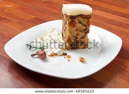 Last piece of christmas cake on plate with crumbs and decorations.