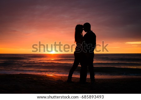 Beautiful romantic couple at sunset by the sea. Dramatic beautiful landscape beach valentines silhouettes concept.
