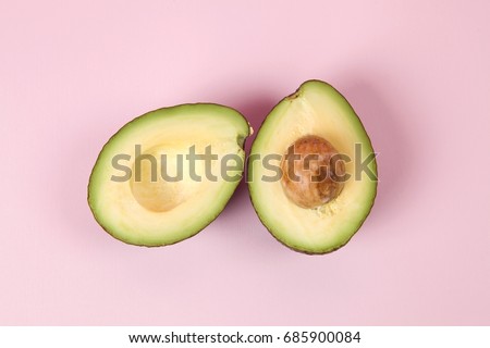 two avocado half with seed on a pink background. minimal color still life photography 