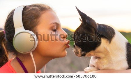 Girl kissing her dog - boston terrier - and listening to music