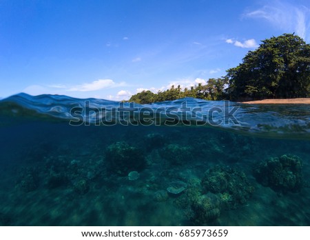 Double landscape with sea and sky. Sea panorama split photo. Undersea view of coral. Tropical island beach. Above and below sea waterline. Blue seawater with coral reef. Exotic island seaside vacation