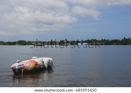 Man paddling a wooden canoe full of plastic