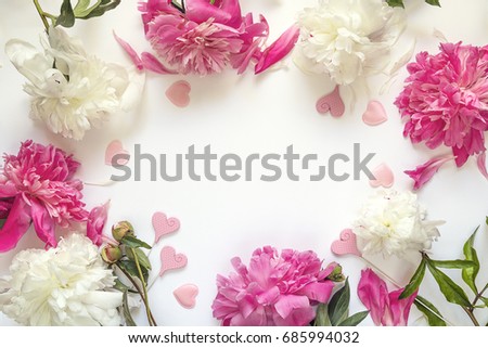 Frame of peonies and decorative hearts on white background. Place for the text. Top view.