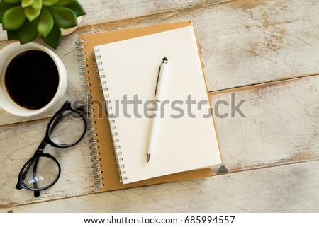 Notebook with glasses and coffee on table