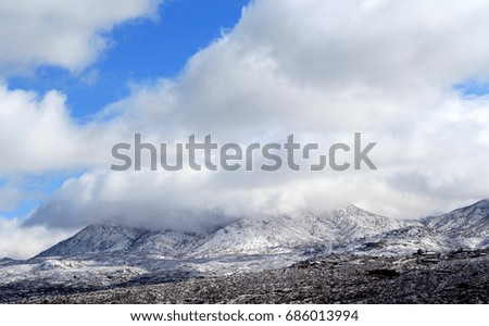 Crisp winter's day with huge puffy white monsoon clouds and blue sky over the snow covered Catalina mountains in the Tucson Arizona desert 