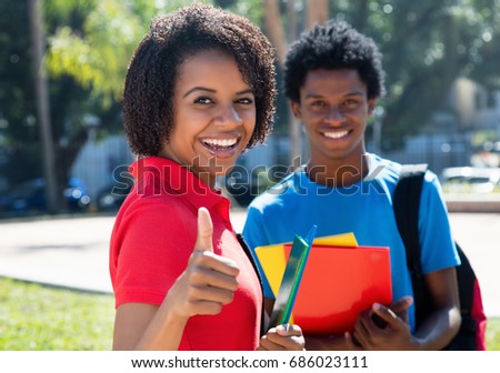 African american female student showing thumb with african male student