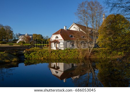 Old stone distillery with reflection in water of pond, Sunny day.