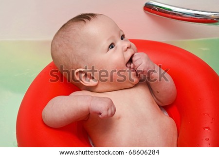 The kid swims in the big bathroom on a red life buoy