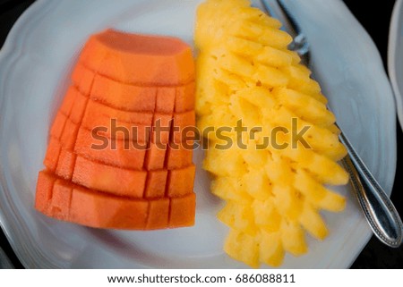 papaya and pineapple. Sliced pineapple on white ceramic plate on wooden table. cut into pieces