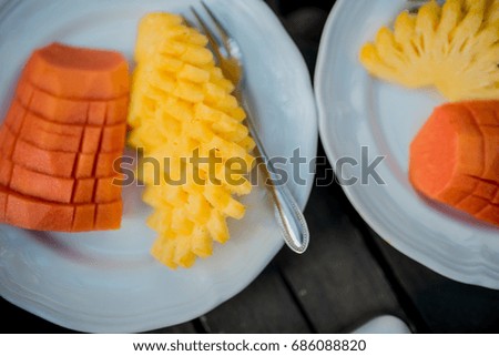 papaya and pineapple. Sliced pineapple on white ceramic plate on wooden table. cut into pieces