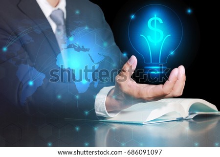 Double exposure of businessman hand hold, glowing blue dollar sign and bulb technology icon as business control, investment and income concept.