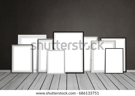 Multiple empty picture frames leaning on wall.