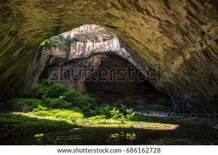 huge cave with holes on top and river inside