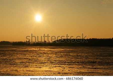 photographed field covered with snow in the winter season. The picture shows the yellow sun during sunset
