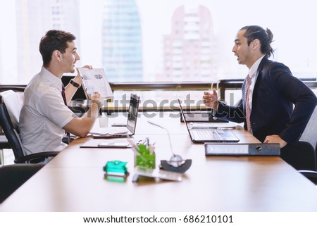 Business people discussing the charts and graphs showing the results of their successful teamwork in meeting room.